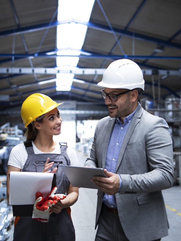 Manager supervisor and worker discussing about production results and new strategy in factory industrial hall.